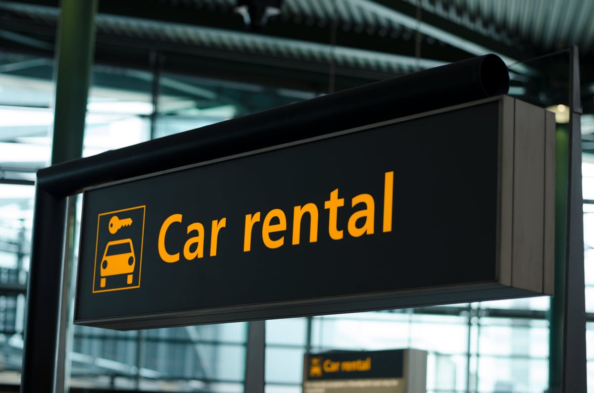 Directional road sign pointing to car rental services
